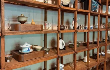 Chaguan in Kyiv - wooden shelves displaying clay teapots and bowls
