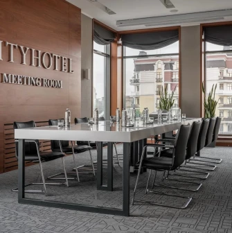 City Hotel in Kyiv - meeting room with long white table, black chairs and wooden wall