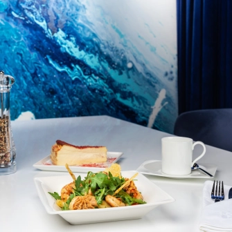 Egersund Seafood - shrimp salad and cheesecake served on white table with ocean-themed wall