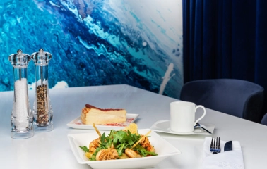 Egersund Seafood - shrimp salad and cheesecake served on white table with ocean-themed wall
