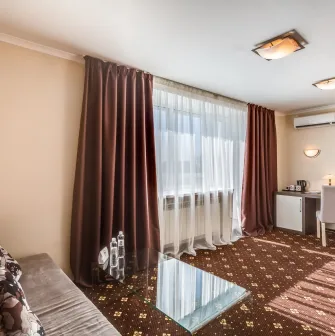 A comfortable hotel room with a sofa, desk, and large window at the Bratyslava Hotel in Kyiv