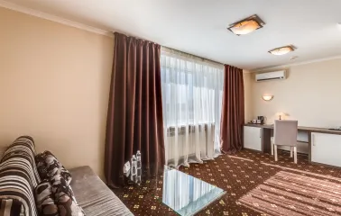 A comfortable hotel room with a sofa, desk, and large window at the Bratyslava Hotel in Kyiv