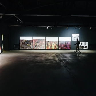 Lavra Gallery in Kyiv - dark industrial exhibition space with abstract paintings and a person on a skateboard