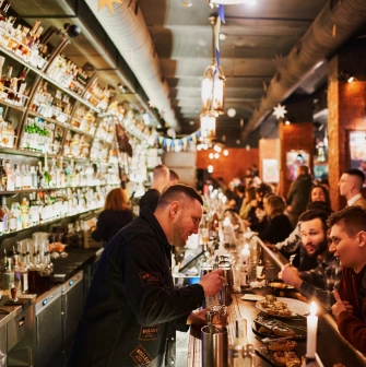 BarmanDictat - bartender preparing a drink while talking to a guest at the bar counter