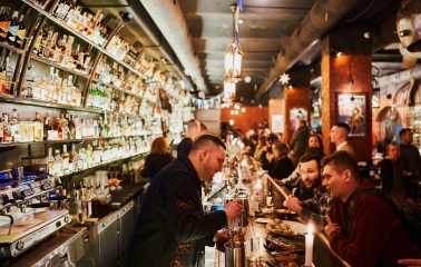 BarmanDictat - bartender preparing a drink while talking to a guest at the bar counter