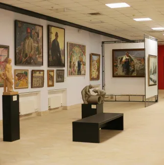 Muzei Suchasnoho Mystetstva in Kyiv - spacious and well-lit main gallery corridor filled with diverse paintings and small sculptures on pedestals