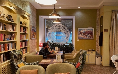 Restaurant Imbyr - restaurant seating area with armchairs a bookcase and natural light from the window