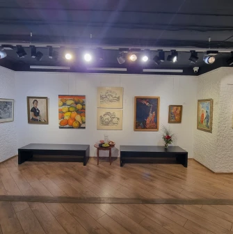 Muzei Suchasnoho Mystetstva in Kyiv - exhibition space with warm lighting featuring a collection of paintings, black benches for rest, and white textured walls
