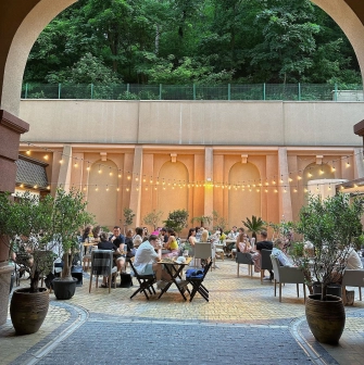 Restaurant Italiets iz Beiruta - view through an arch of the outdoor dining patio with strung lights