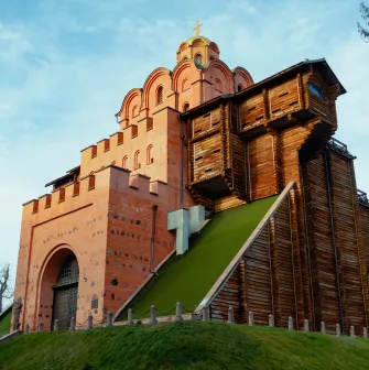 Golden Gate in Kyiv - reconstructed medieval gate with red brick walls, wooden fortifications and grassy slope