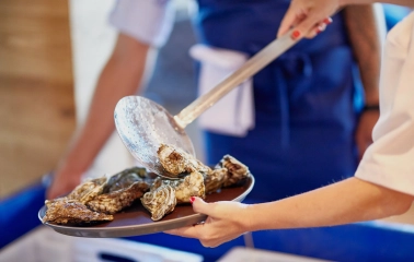 Restaurant Prychal - chef placing fresh raw oysters onto a serving plate with a slotted spoon