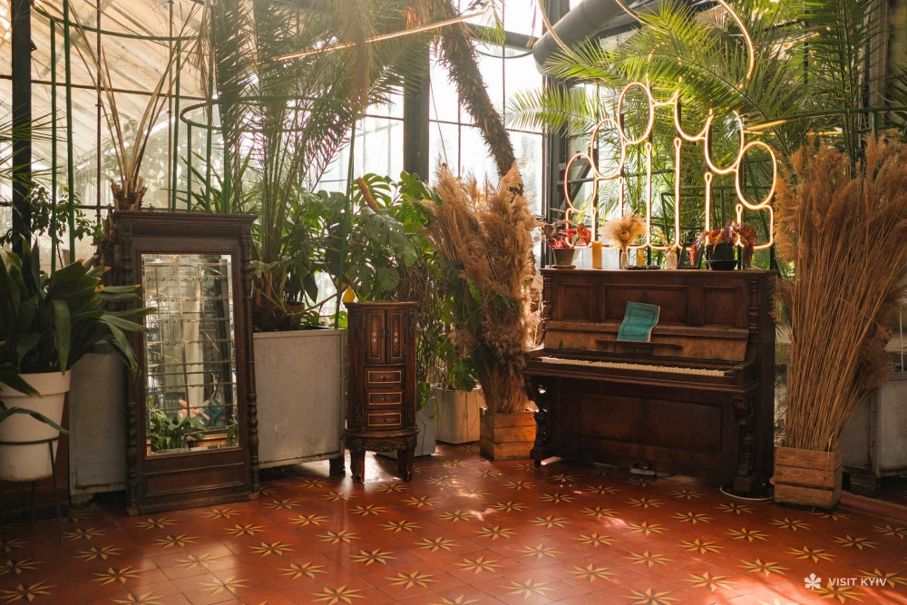 Vintage piano inside the Greenhouse at VDNG in Kyiv surrounded by plants