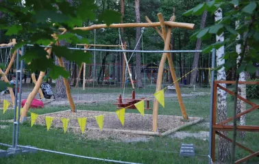 Park Partyzanskoi Slavy in Kyiv - wooden play area featuring tall swings and climbing structures set amongst the pine trees