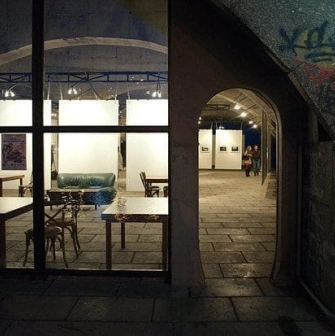 Night view of the ARTPRYCHAL art space in Kyiv with illuminated interior and arched entrance