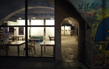 Night view of the ARTPRYCHAL art space in Kyiv with illuminated interior and arched entrance