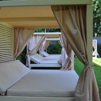 Comfortable bed loungers with canopies on a lawn in the park