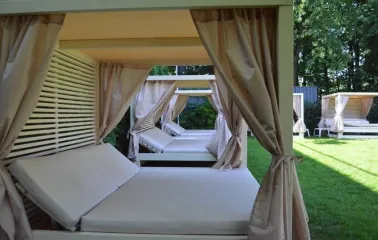 Comfortable bed loungers with canopies on a lawn in the park