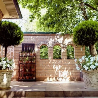 Vozdvyzhenskyi in Kyiv - garden terrace with a brick wall, arched mirrors, and potted white flowers