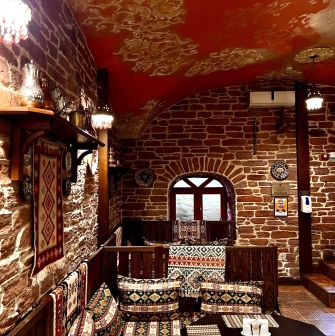 Sofra in Kyiv - dining area with brick walls, wooden seats and patterned textiles