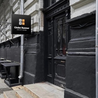 The entrance to the Globe Runner hostel in Kyiv with a sign and a black door