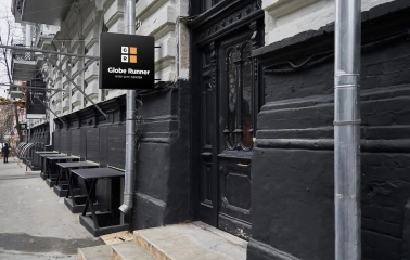 The entrance to the Globe Runner hostel in Kyiv with a sign and a black door