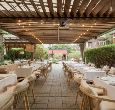 View of an outdoor restaurant terrace with white tablecloths and greenery