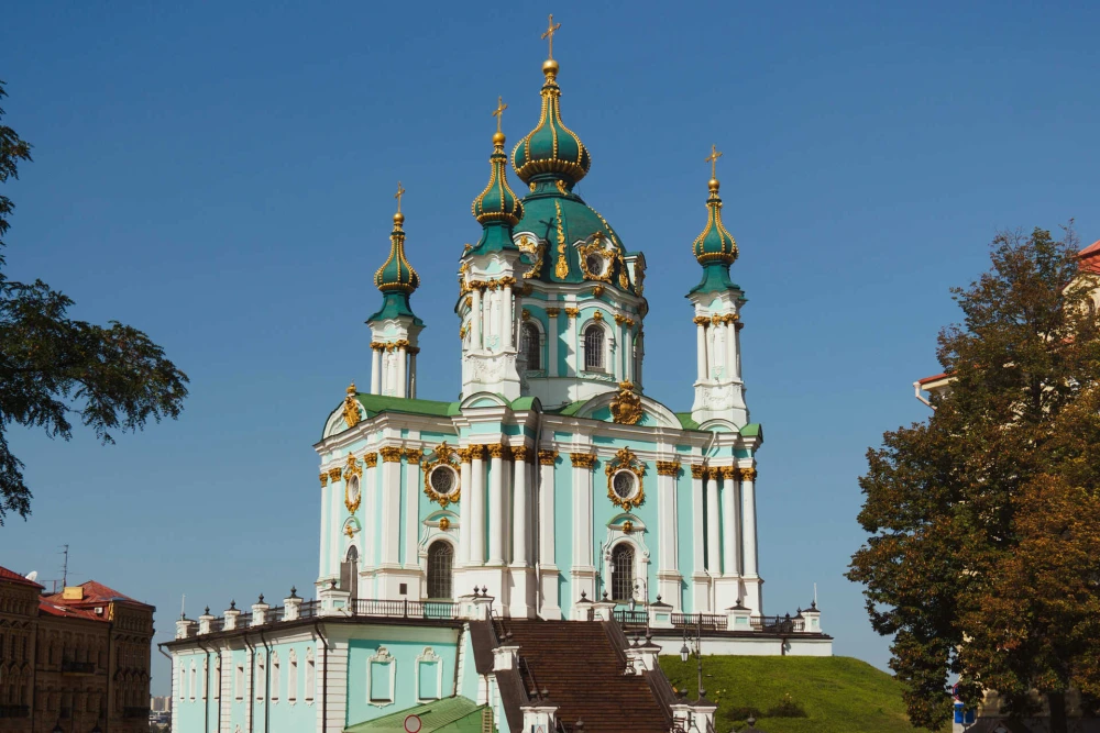 St. Andrew's Church in Kyiv with turquoise walls and golden domes against blue sky