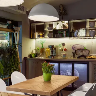 Ulyublenyi Diadia – cozy dining area with plants and open kitchen shelves