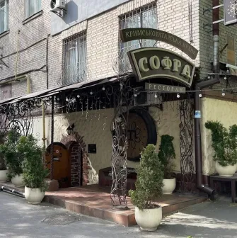 Sofra in Kyiv - restaurant entrance with forged metal arch, sign and potted plants