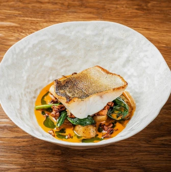 Restaurant Poltava - white fish fillet with crispy skin served in a bowl on a wooden table