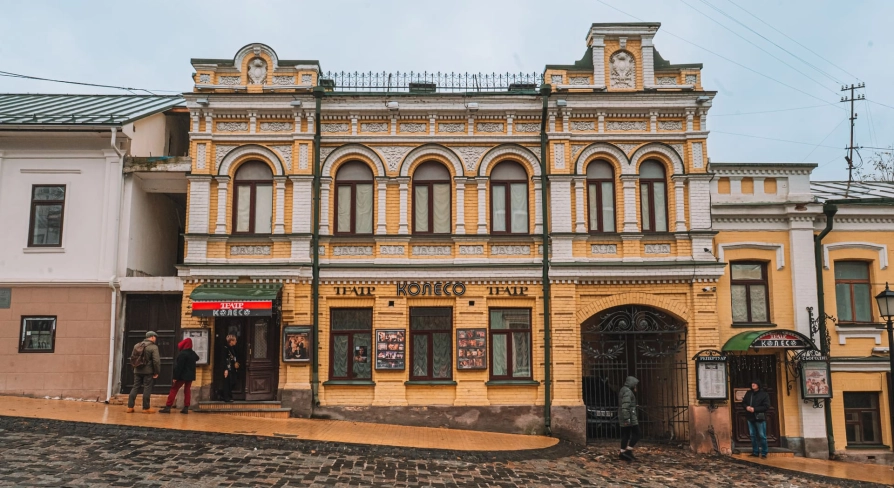 Koleso Theater in Kyiv - full view of historic yellow building on cobbled street
