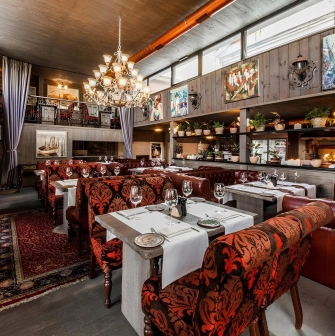 Restaurant Kanapa - dining room with tables leather couches and paintings on the wooden walls