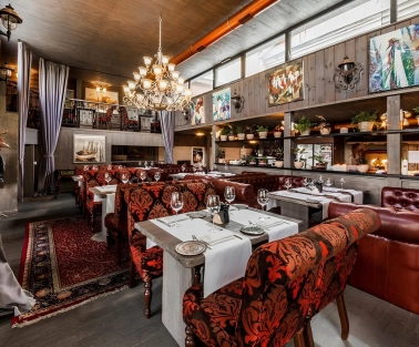 Restaurant Kanapa - dining room with tables leather couches and paintings on the wooden walls