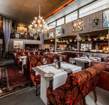 Restaurant Kanapa - dining room with tables leather couches and paintings on the wooden walls