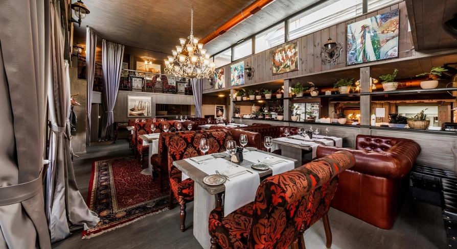 Restaurant Kanapa - dining room with tables leather couches and paintings on the wooden walls