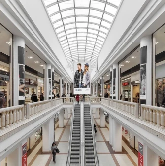 Gallery of shops in the Globus shopping center with an escalator and a light roof