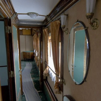 Railway Museum in Kyiv - narrow vintage train corridor lined with wood paneling, mirrors, and beige curtains evoking the atmosphere of past travel