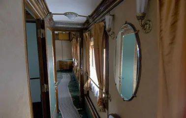 Railway Museum in Kyiv - narrow vintage train corridor lined with wood paneling, mirrors, and beige curtains evoking the atmosphere of past travel