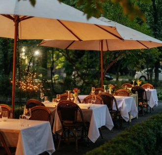 La Veranda - spacious outdoor terrace with wicker chairs and tables under umbrellas