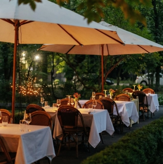 La Veranda - spacious outdoor terrace with wicker chairs and tables under umbrellas