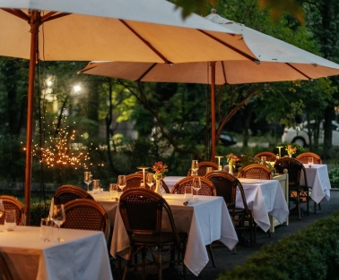 La Veranda - spacious outdoor terrace with wicker chairs and tables under umbrellas