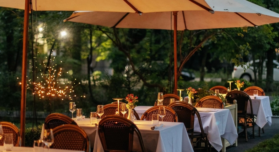 La Veranda - spacious outdoor terrace with wicker chairs and tables under umbrellas