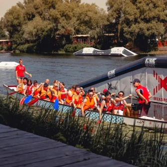 X-Park in Kyiv - team in orange life vests rowing a dragon boat on the river
