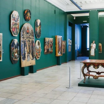 Natsionalnyi Khudozhnii Muzei Ukrainy in Kyiv - spacious gallery hall with green walls displaying ancient religious icons and a carved wooden table