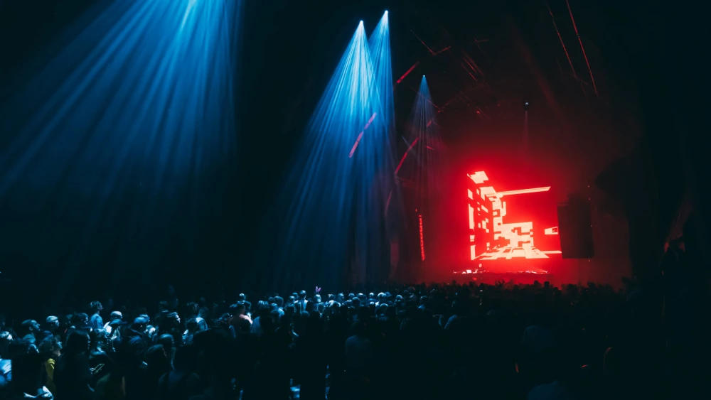 Electronic music concert with bright red screen and blue stage spotlights