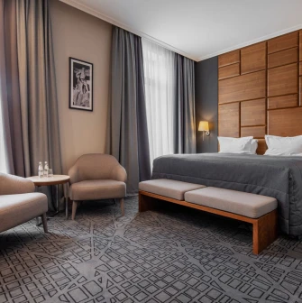 City Hotel in Kyiv - bedroom with large double bed, wooden wall panel and two armchairs