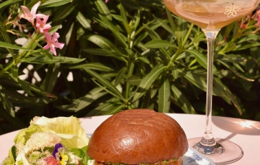 Namelaka - salmon burger with fresh salad and wine glass on pink table