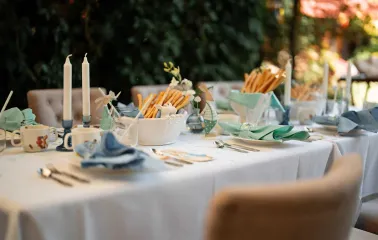 A table set for dinner with candles, breadsticks, and soft blue napkins