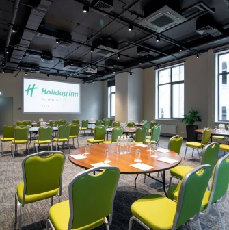 Conference hall with a projector and green chairs at Holiday Inn