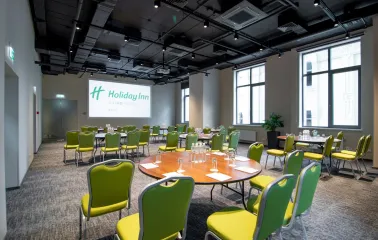 Conference hall with a projector and green chairs at Holiday Inn